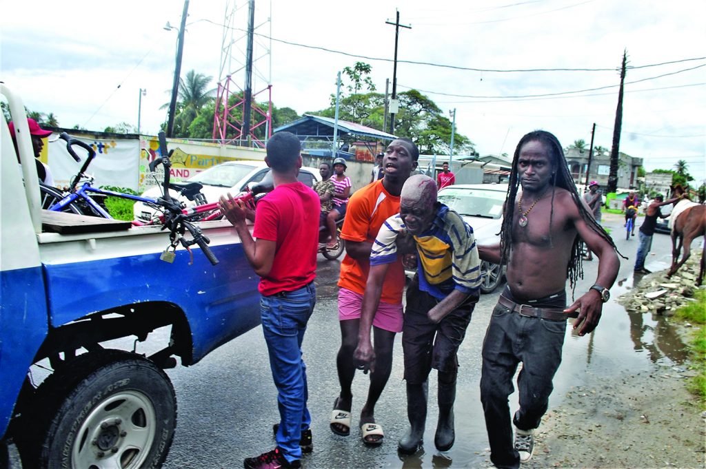 Public-spirited citizens assisting the injured pedestrian to the waiting Police patrol vehicle