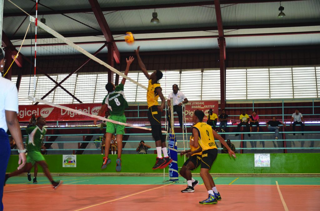 UP IN RIVALRY! A Guyanese player (yellow and black) about the tip the ball over the net while a Surinamese player aims to block.