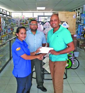 Rafeek Kassim (right) happily collects sponsorship from member of staff of A Ally and Sons Showroom in the presence of Managing Director Waqar Sahid 