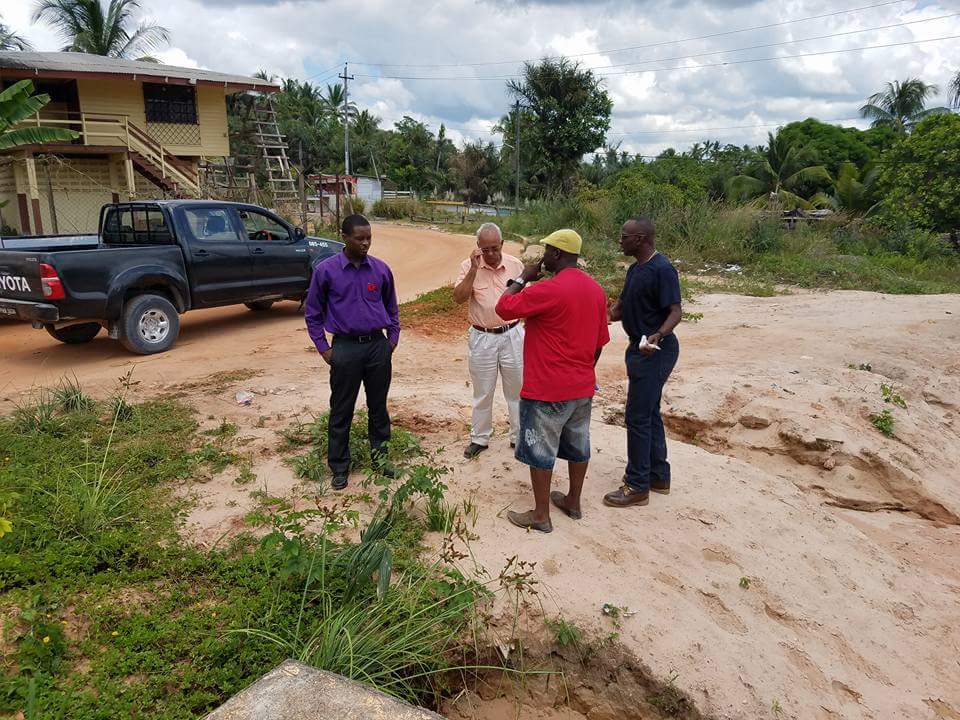 Mayor Carwyn Holland, Dr Sewnauth Punalall and Councillor Wainwright Bethune (in black) stand with a resident during a visit to communities affected by erosion