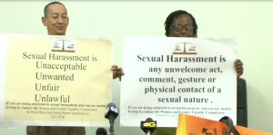 Commissioners holding up draft posters with anti-sexual harassment slogans 