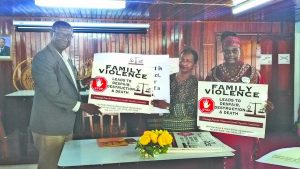 Chairperson of the Commission, Indra Chandarpal presents the posters to Regional Executive Officer Rupert Hopkinson at the launch of the campaign