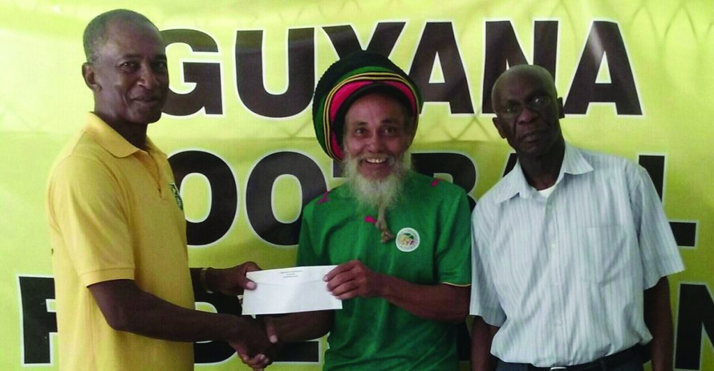GFF’s Executive Committee member Keith O’Jeer (left) makes a presentation on behalf of the GFF to chief tournament Organiser, Ras Wadada in the presence of GFF’s GS, Ag, Trevor King 