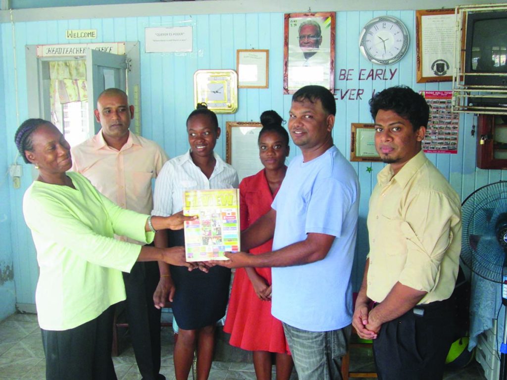 RHTY&SC Executive Mark Papannah hands over a copy of the Magazine to Deputy Head Teacher of Lower Corentyne Secondary School, Sharon Hawke in the presence of other staff members 