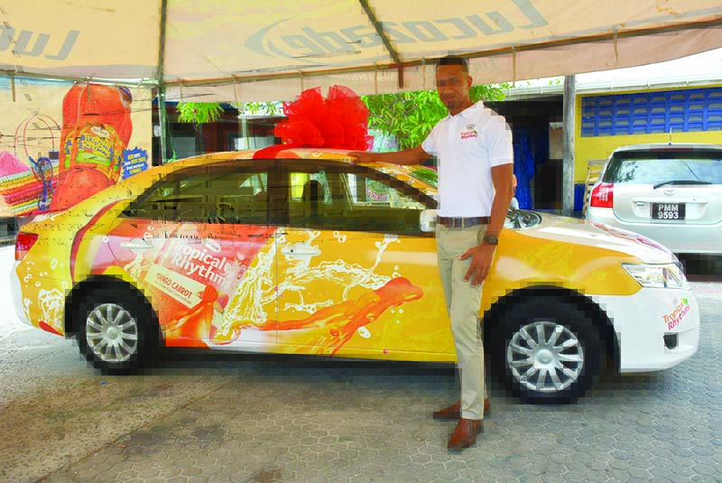 Tropical Rhythm Brand Coordinator, Sean Abel, stands next to the grand prize in the “Christmas Dreams New Year’s Wishes Promotion”