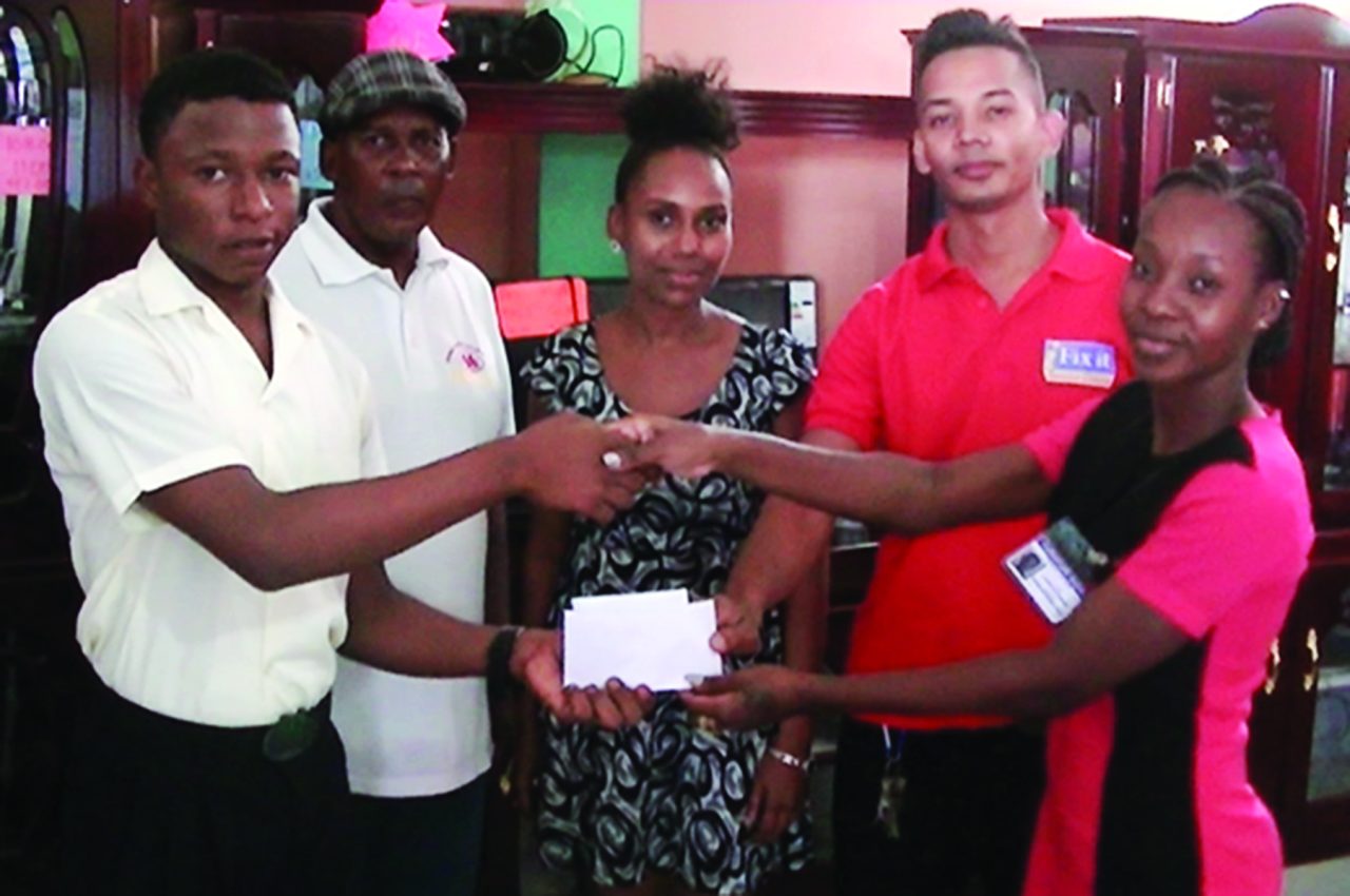 Leone Civriana of Fix It Electronic Service and Janette Blackman of Furniture World hand over a sponsorship check to a member of FACC which coach Randolph Roberts and Janette Ikel of Furniture World look on 