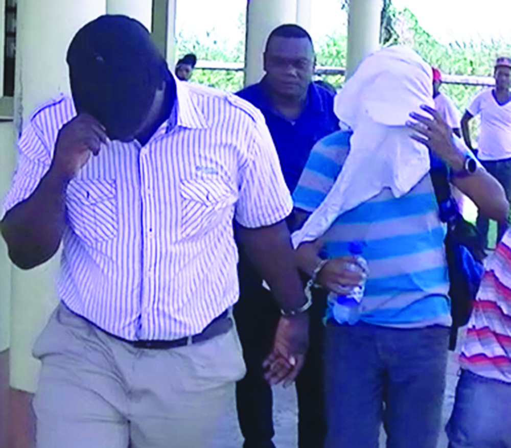 The two officers covered their faces as they are being led away by Detective Sergeant Lawrence Thomas