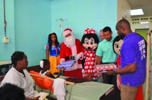 A young boy collecting a present from Santa Claus and other Courts Guyana Inc staff 