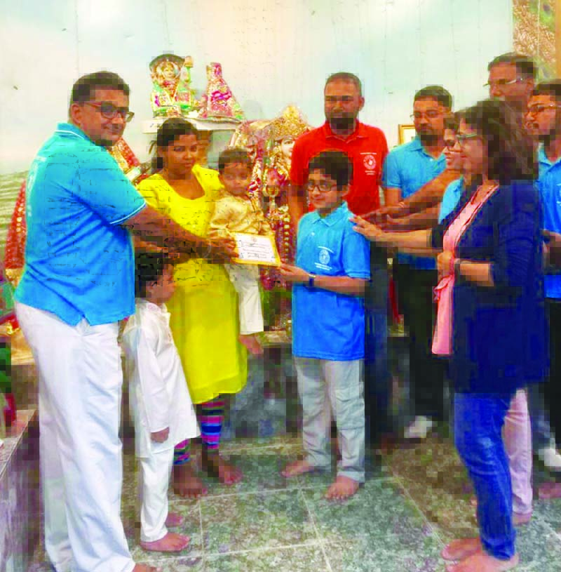 Pandit Sharma and others of his organisation hand over the donation to Omkar Persaud and mother Cassandra Persaud 