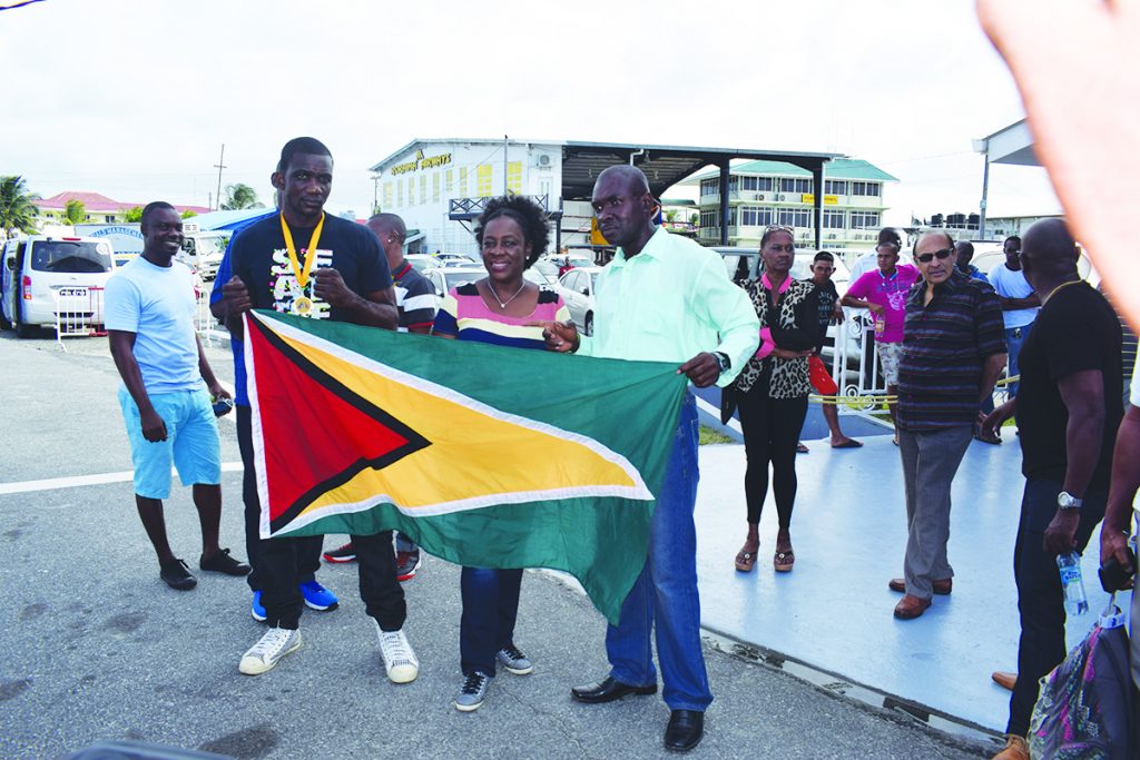 Minister Nicolette Henry (centre) waves the Guyana flag with one of the boxers