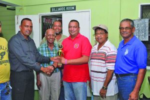 Everest Cricket Club President Rajesh Singh (right) hands over the winning trophy to Boodnarine Persaud, who collected on behalf of the victorious team. Skipper Manniram Shew is second from right 