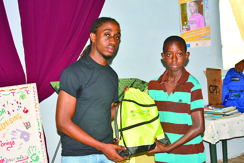 A child receiving his backpack filled with school items from CYA representative Edain Alfred 