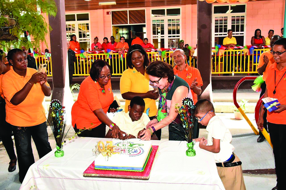 First Lady Sandra Granger cuts the 50th anniversary cake with a student of the Centre, much to his delight