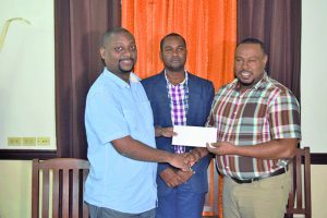 Flashback! New Guyana Pharmaceutical Finance Manager Dwayne Lovell (left) does the ceremonial hand over of sponsorship to Co-Director of Petra Organisation Troy Mendonca in the presence Guyana Football Federation (GFF) Wayne Forde  