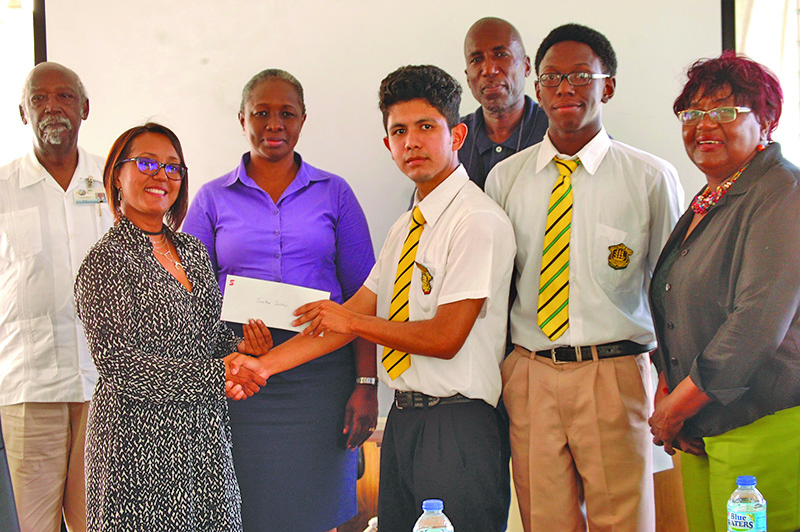 Winners of the logo competition, Omari Joseph and Jonathan Jacobas receive their prize from Scotiabank Marketing Executive Jennifer Cipriani 