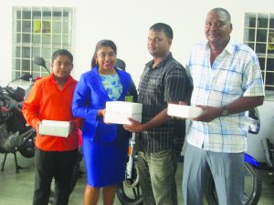 Mings Products and Services Limited Human Resources staff Yvonne Ramnarine hands over the cricket balls to Mark Papannah, Simon Nahdu and Sohan Harry 
