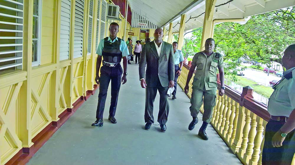 State witness and gang member Clebert Reece leaving the High Court in Georgetown on Thursday afternoon, escorted by Police