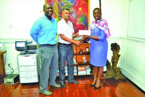 Minister Nicolette Henry (right) hands over the cheque to Secretary of the GCB Anand Sanasie while GCB Territorial Development Officer, Colin Stuart look on 