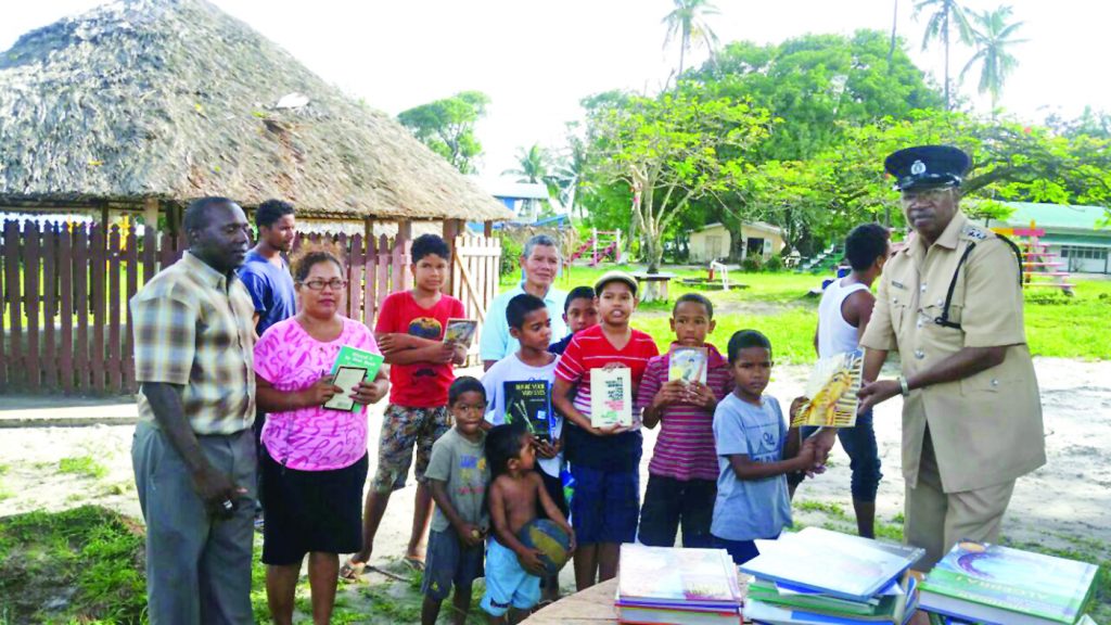 Chief Inspector Clarence Hutson presenting the books to the children of Capoey 
