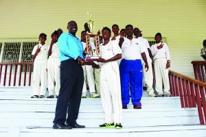 Guyana Cricket Board (GCB) Territorial Development Officer (TDO), Colin Stuart, presents East Coast captain, Davenand Khemraj with the winning trophy with the rest of the team in the foreground 