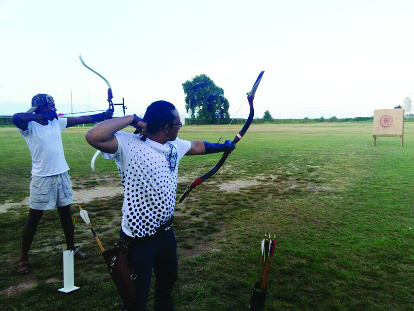 Nicholas Hing (right) after releasing an arrow during an Outdoor Archery Training 