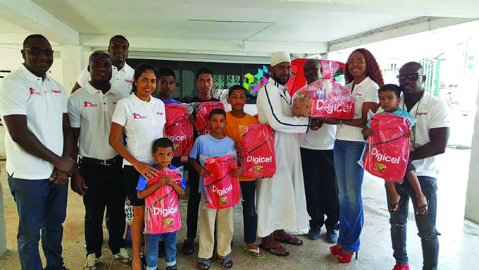 Digicel Head of Marketing Jacqueline James, staff and Brand Ambassadors Jumo Primo and DJ Casual with administrators and boys of the Shaheeds Boy’s orphanage  
