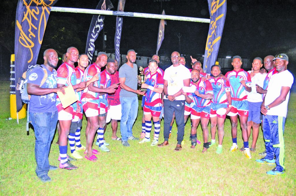 All smiles! Captain of the Pespi Hornets Ryan Gonsalves collects the championship trophy from Director of  Sports Christopher Jones, in  the presence of Guinness Brand  Manager Lee Baptiste (Photo compliments of Orlando Charles) 