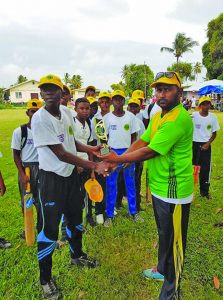 Leguan Secondary School captain Malcolm Cesar (left) receives the winning trophy from Zaheer Zakier, the scorer