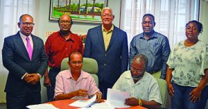 An agreement was on Friday signed between the Hope Coconut Industries Limited and the Caribbean Agricultural Research and Extension Institute to expand the existing coconut nursery at Hope Estate. Overlooking the signing is Agriculture Minister Noel Holder (standing centre)