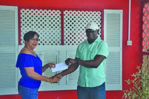 Desrie Lee (left) collects the cheque from Mohamed’s Enterprise representative Udoh Kanu at the GMR&SC headquarters