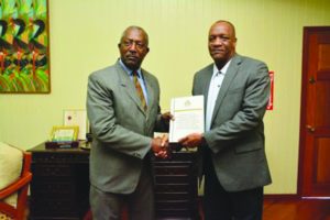 Minister of State Joseph Harmon receiving the report from Colonel (retd) Desmond Roberts at the Ministry of the Presidency on Friday  