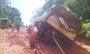 An overladen truck stuck in the muddy conditions of a hinterland road